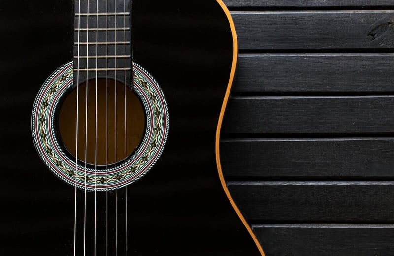 black acoustic guitar on black finished wood background