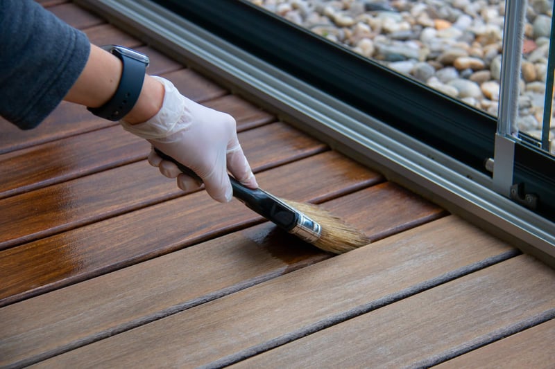 person applying wood finishing product on decking