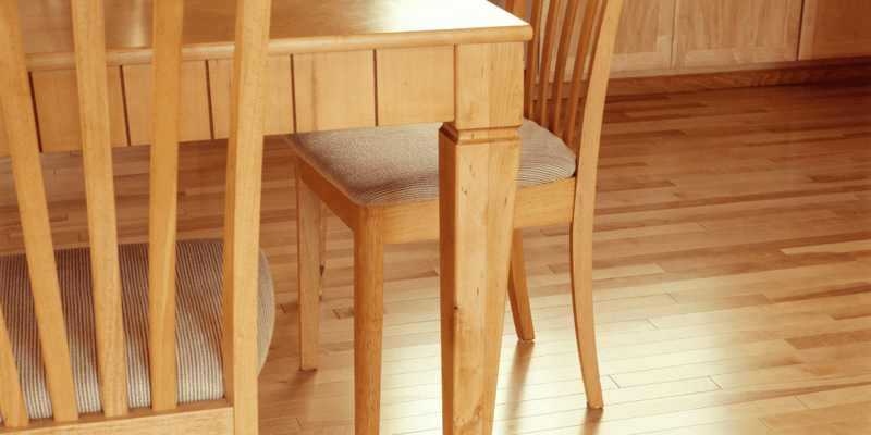 room interior close-up of dining set chairs and matching table with shiny maple color wood finishes